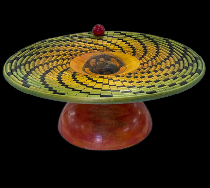 A turned wood sculpture representing the theme "hunger Moon". A red hemisphere (sun) supports a dark green/blue sphere (earth) which in turn penetrates an 18" turned disc that is carved and decorated with a spiral design representing the top of a saguaro cactus. in the center of the disc is a hand cradling the cold dry polar region
